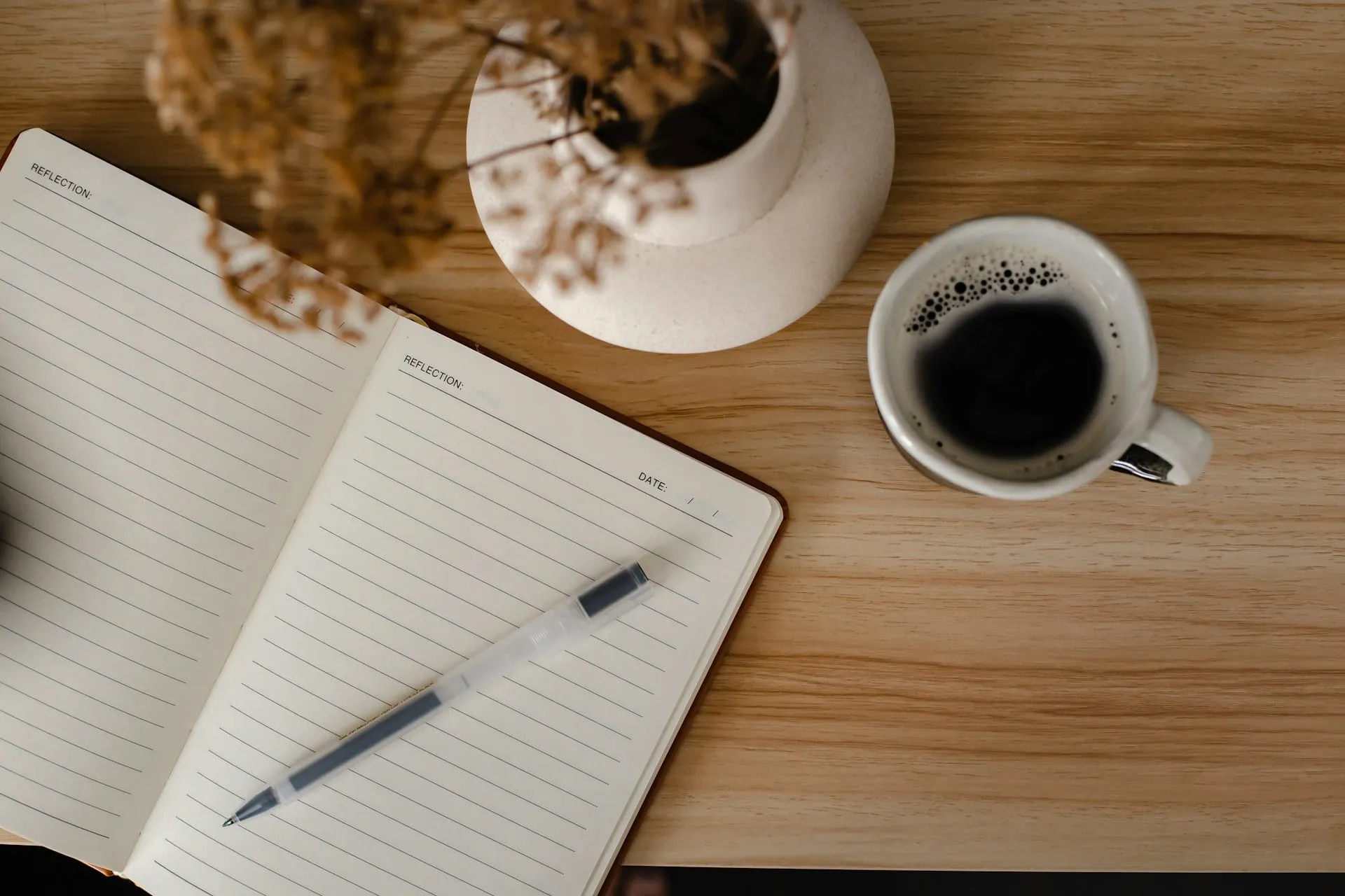 An open notebook and a cup of coffee on a wooden table